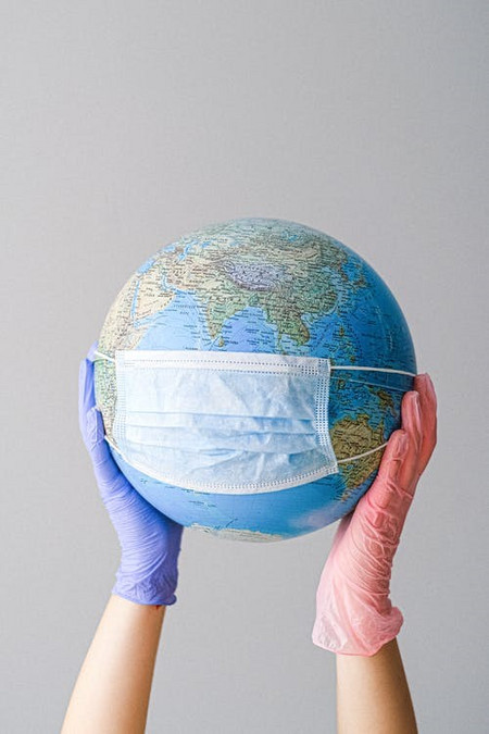 two gloved hands holding a masked globe
