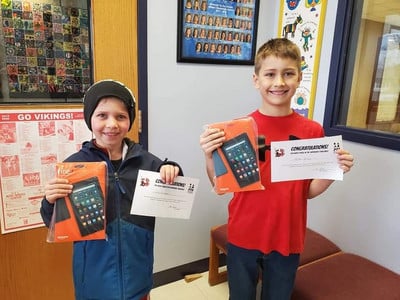 two elementary students holding up PTA award certificate and prize